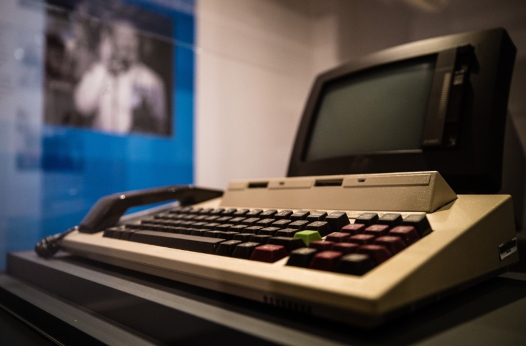 A combined computer, keyboard and telephone handset with a black monitor screen.