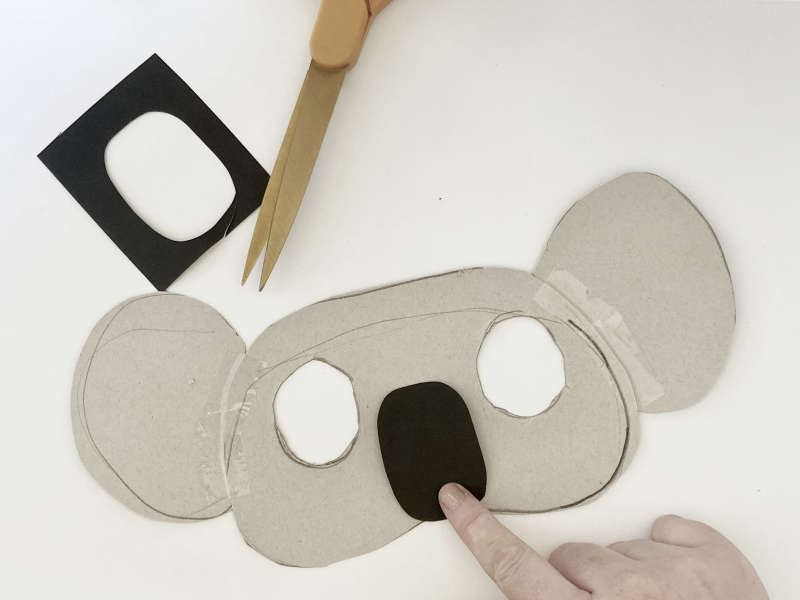 A koala mask with two eye holes cut out and a black nose. 