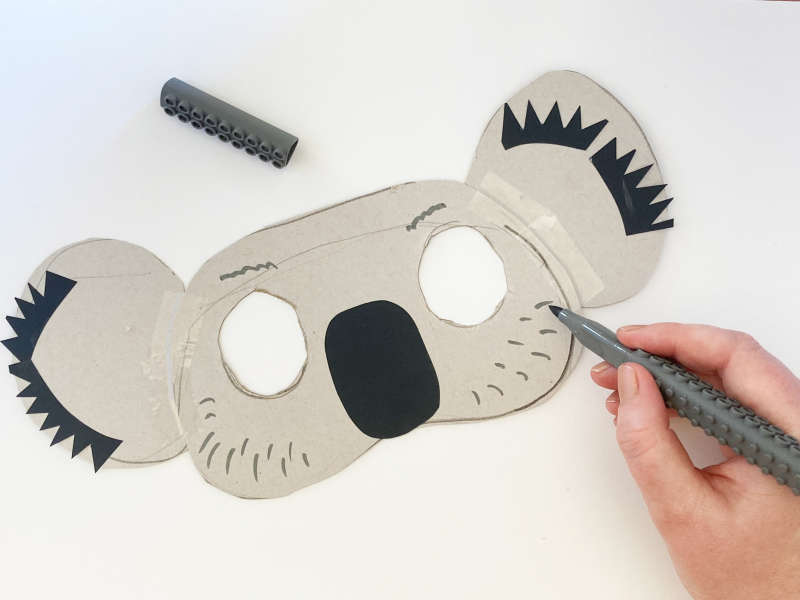 A koala mask with eyes cut out, black nose, black ears. 