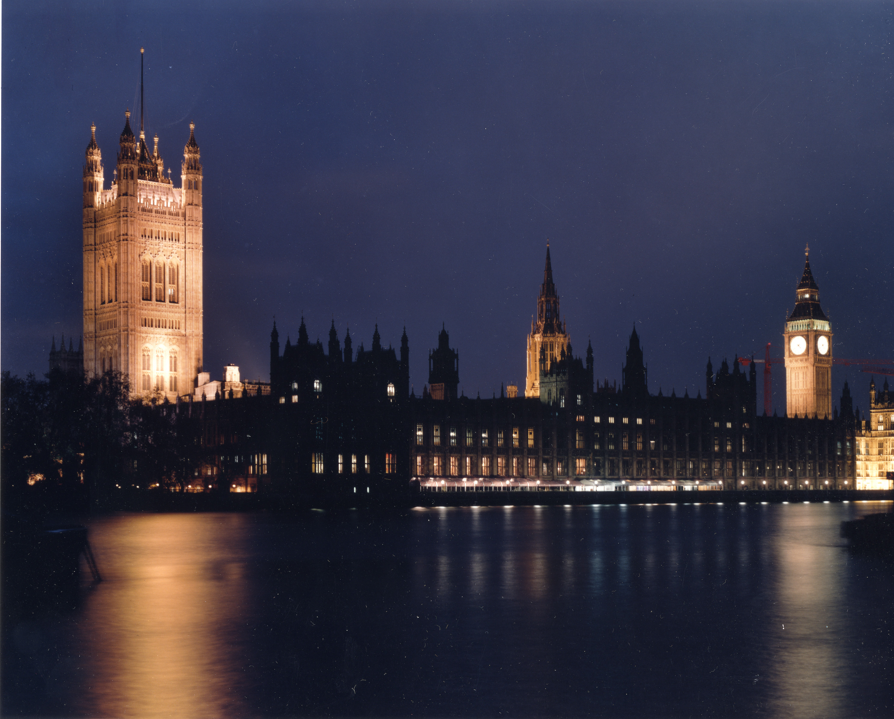 Westminster Abbey, London, at night from across the Thames River.