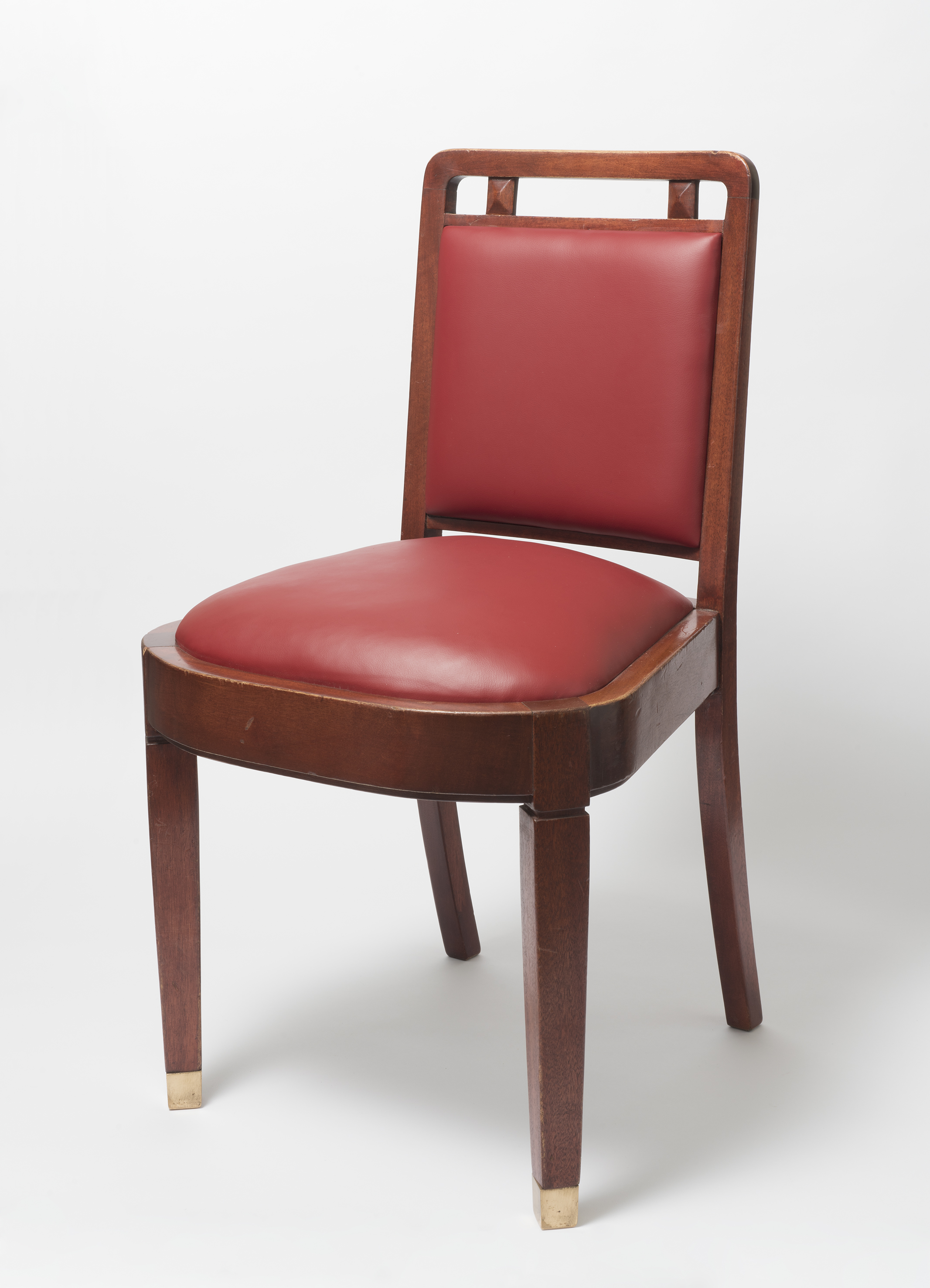 Photograph of a wooden chair with red leather seat cushion and back.