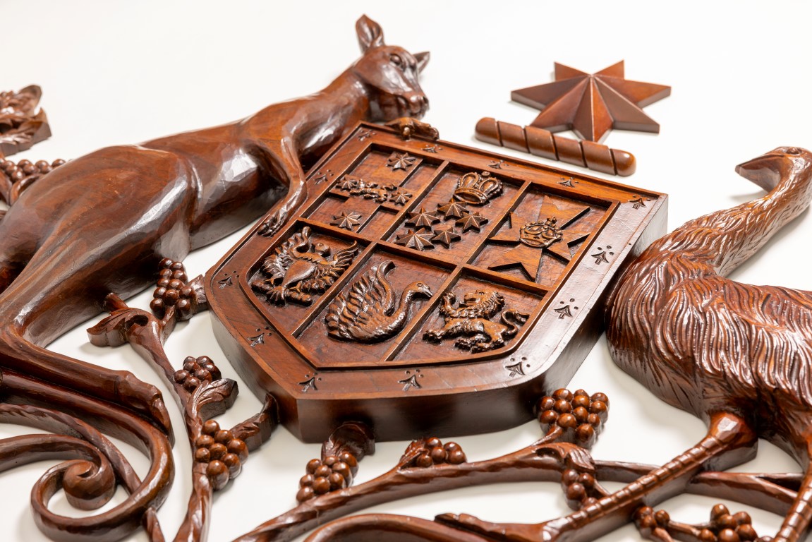 A close up of a wooden coat of arms with a kangaroo and an emu on either side of a shield. A close up of a wooden coat of arms with a kangaroo and an emu on either side of a shield.