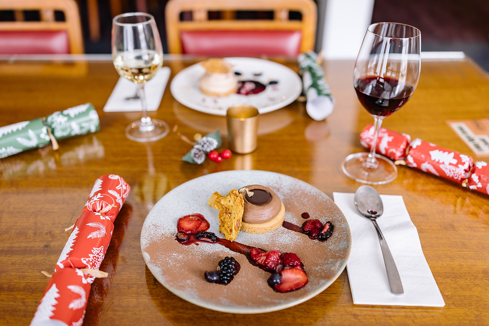 Dessert, wine glasses and Christmas crackers on a restaurant table. 
