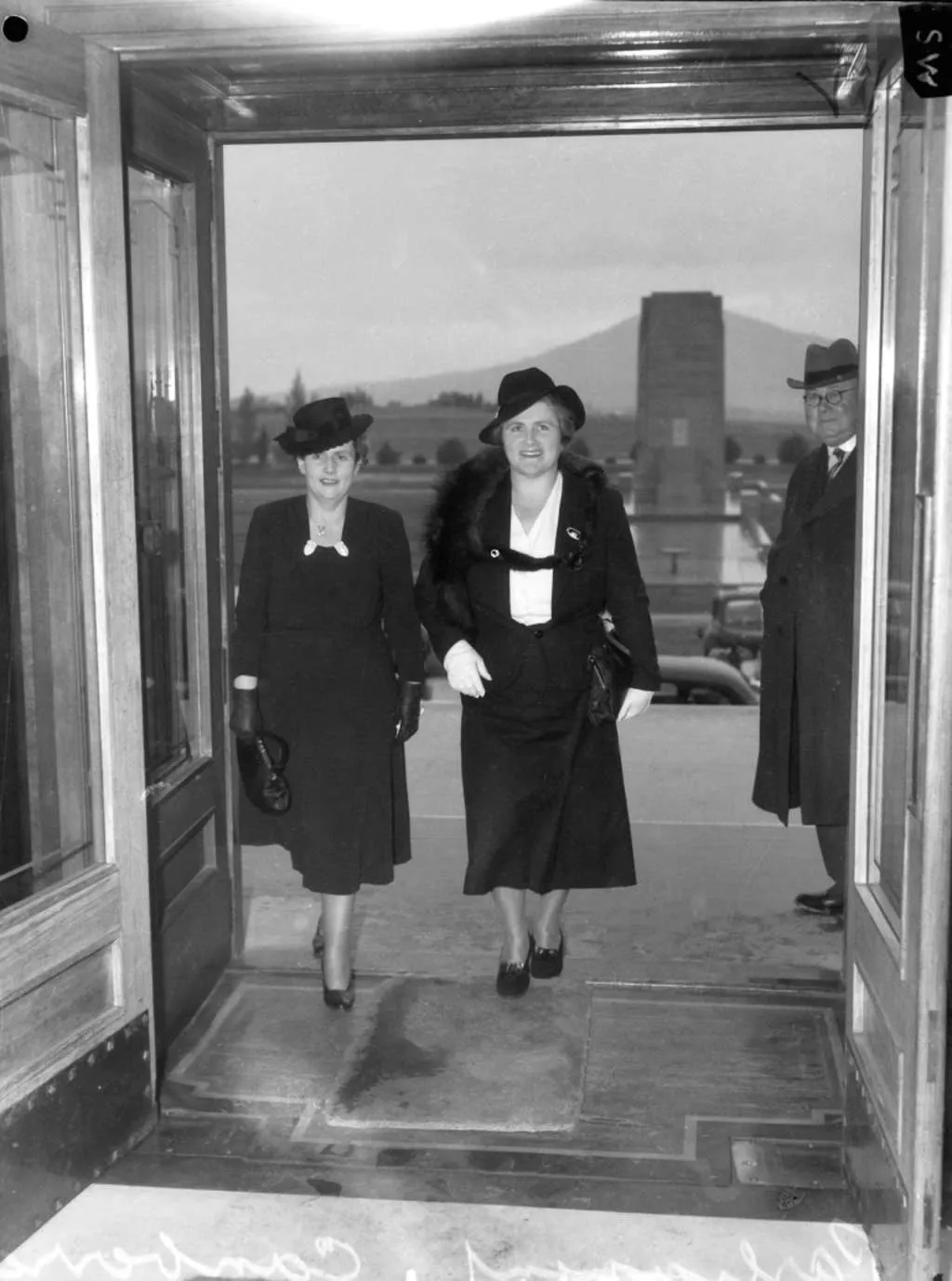 Dorothy Tangney and Enid Lyons walk through the front door of Old Parliament House together in 1943 smiling. 