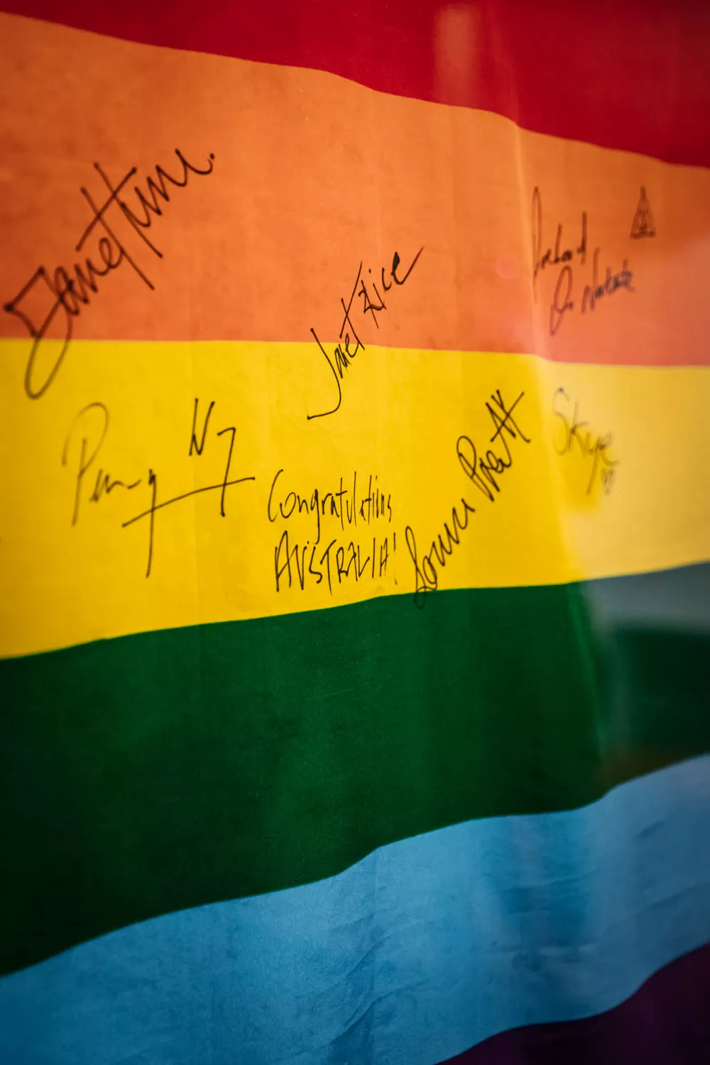 A close up of a rainbow flag covered in signatures. 