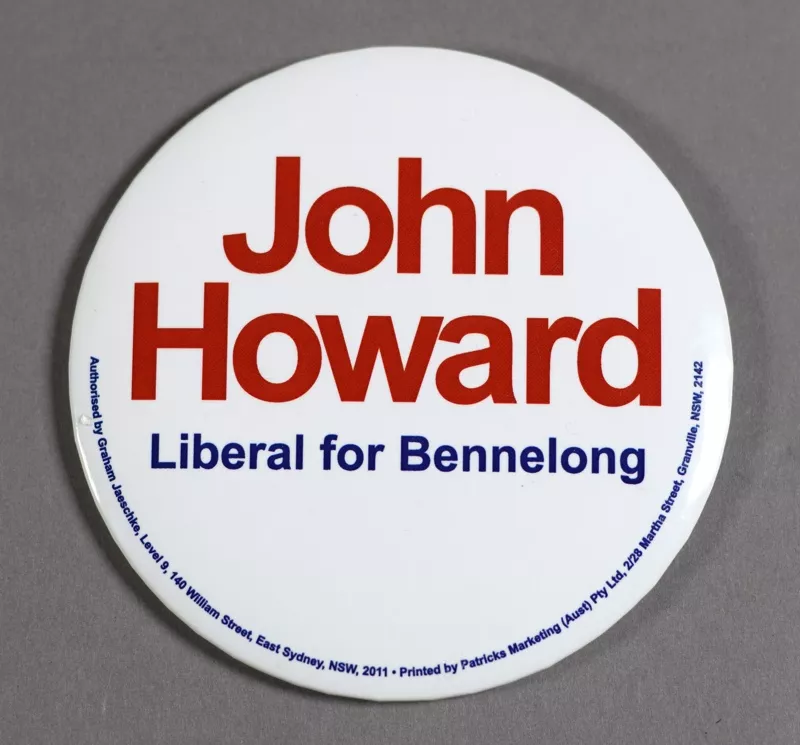 A white badge with the words 'John Howard' in red and 'Liberal for Bennelong' in blue letters.