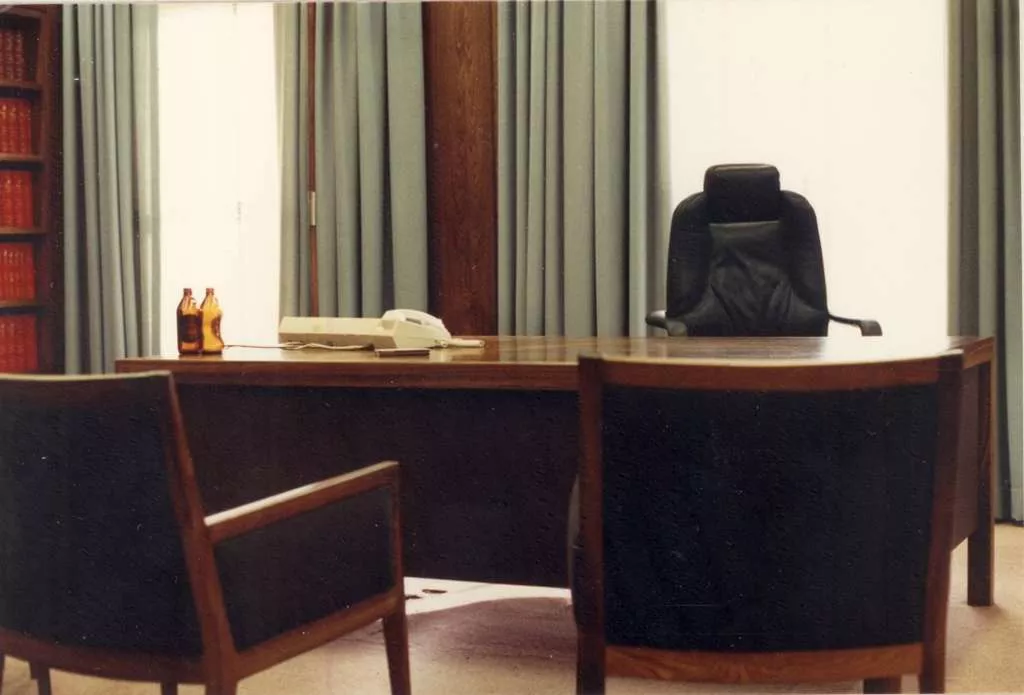 The Prime Minister's wooden desk, cleared of everybody but a telephone and two empty beer bottles.