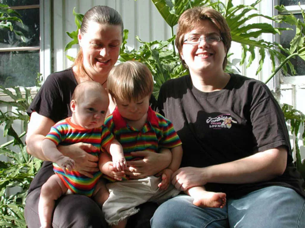 A family photo of two women and two young children in rainbow shirts