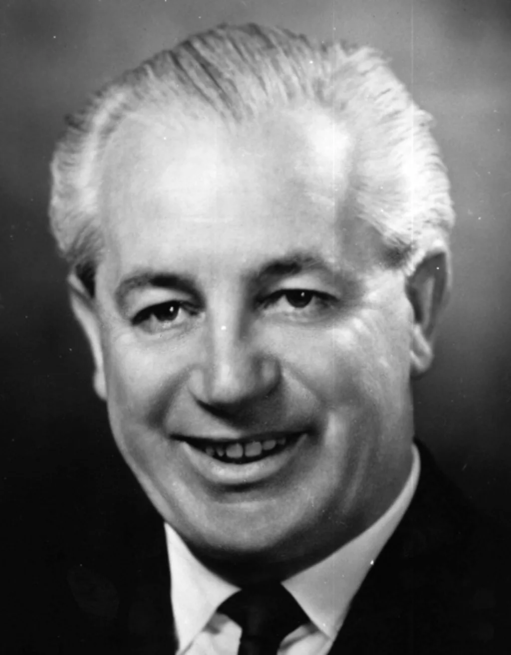 Black and white headshot portrait of Harold Holt, wearing a black tie and suit.