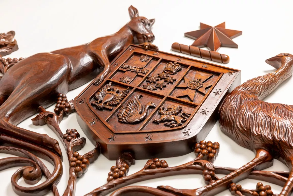 A close up of a wooden coat of arms with a kangaroo and an emu on either side of a shield. 