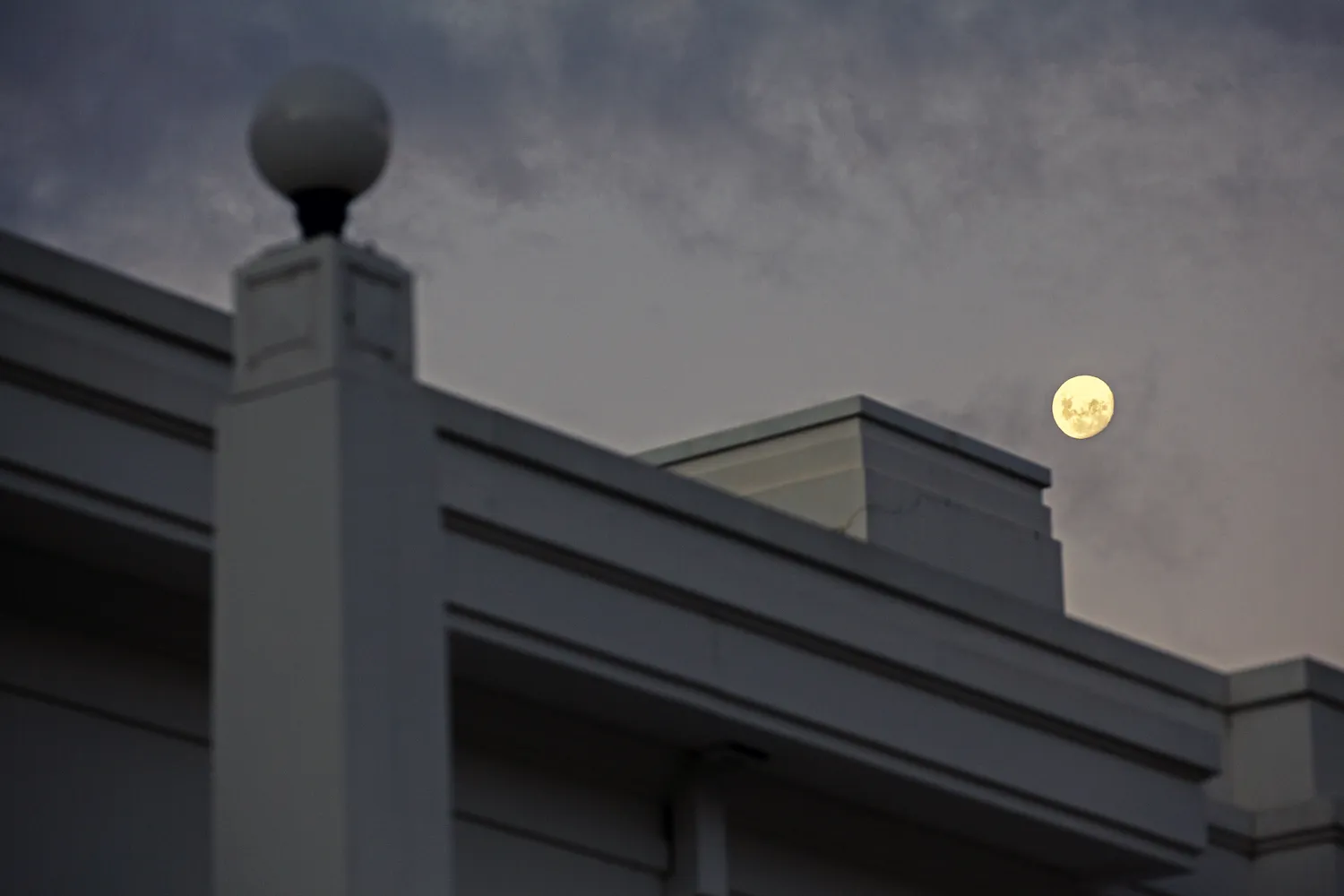 A section of the Old Parliament House building, with the moon in the night sky in the background.