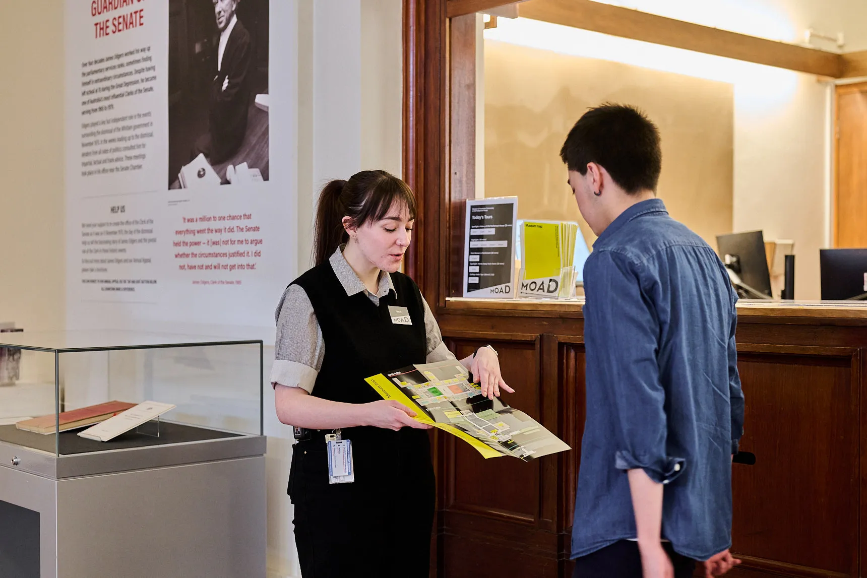 A staff member in King's Hall shows a visitor a map of Old Parliament House.