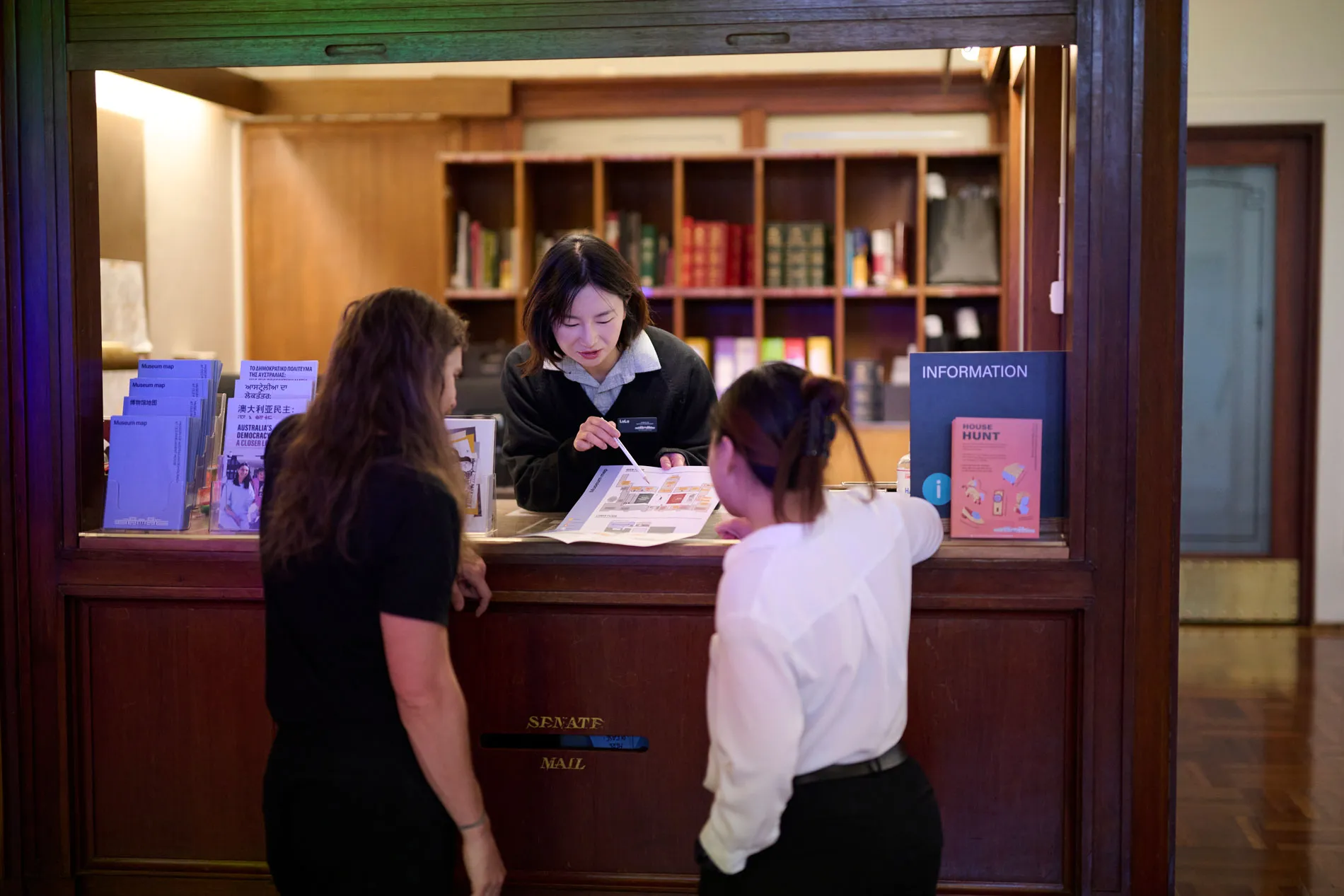 A museum staff member shows a map to visitors in King's Hall at Old Parliament House.