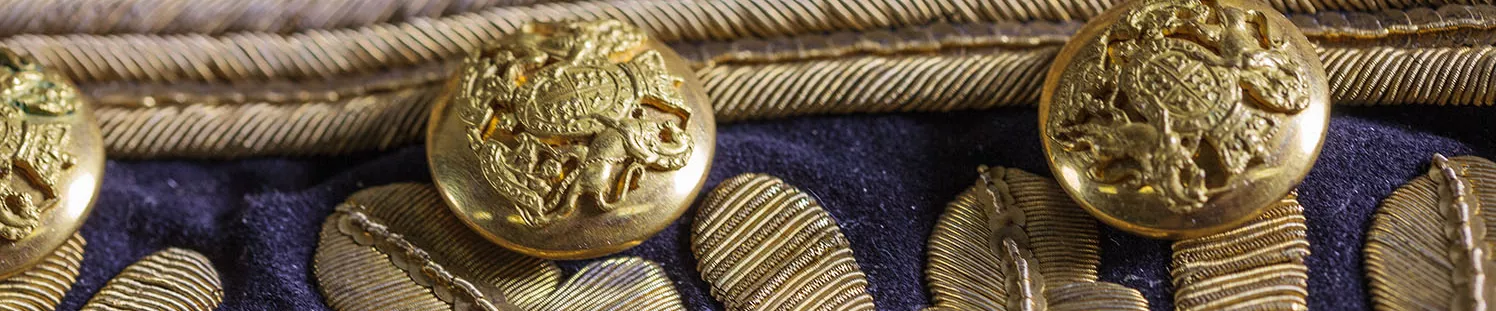 A close-up of an ornate coat with gold embroidered leaves and gold buttons embossed with the Australian coat of arms.