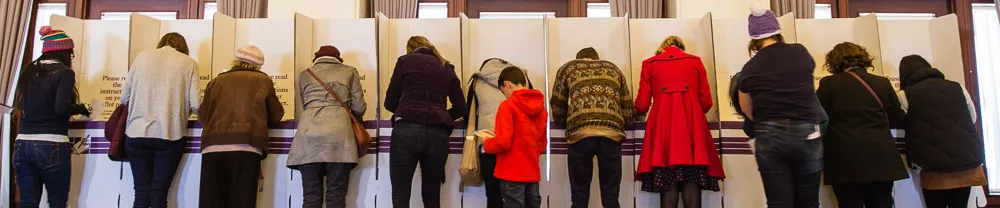 The backs of people as they vote in cardboard voting booths inside Old Parliament House. 