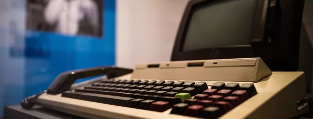 A combined computer, keyboard and telephone handset with a black monitor screen.