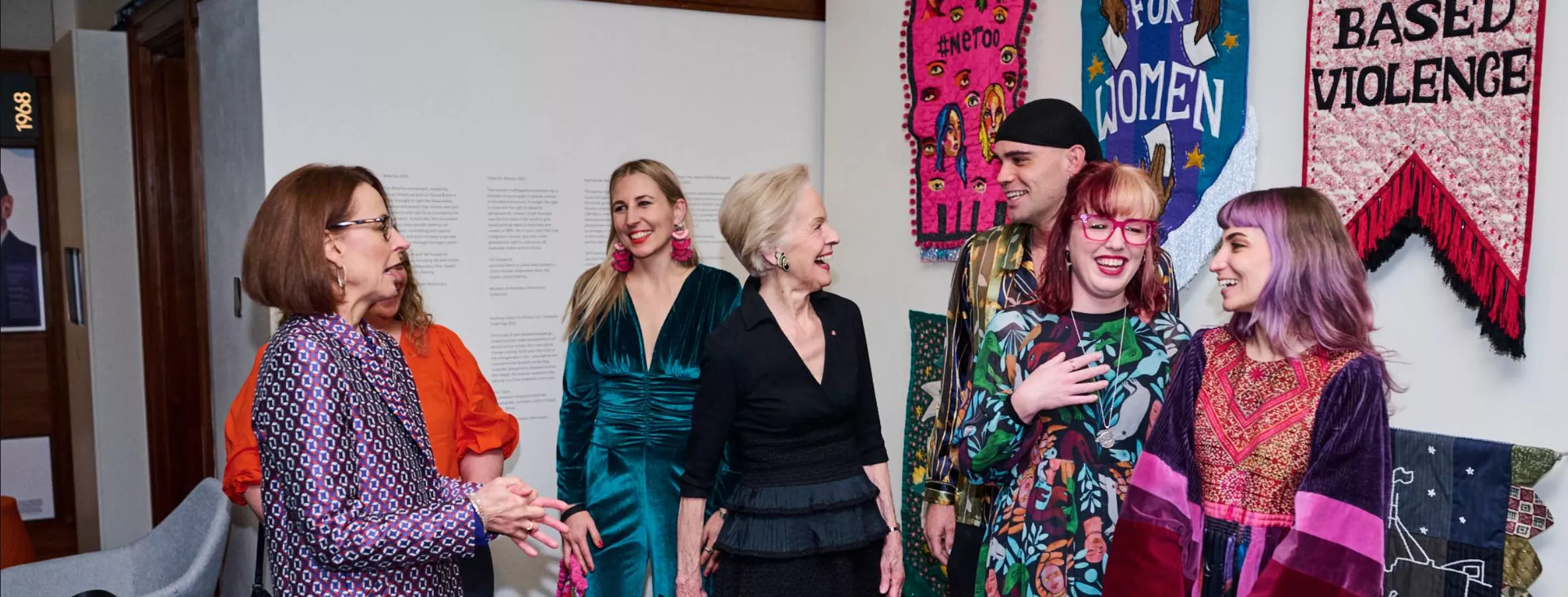 Quentin Bryce chats to artists in front of embroidered banners at the front of the Changemakers exhibition at MoAD.