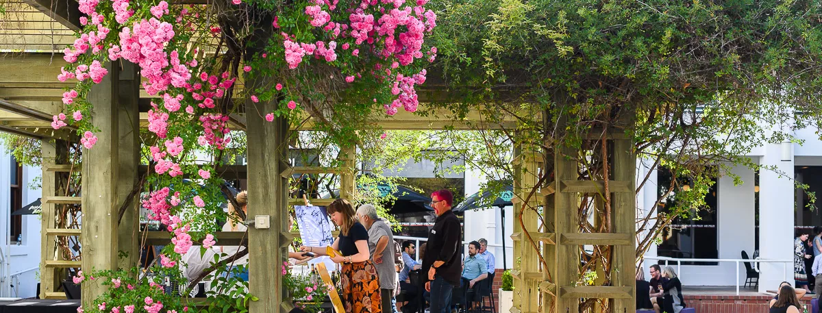 An outdoor bar with pink flowers around a gazebo.