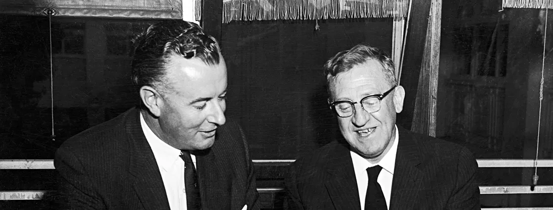 Arthur Calwell and Gough Whitlam are both holding and looking at some papers.