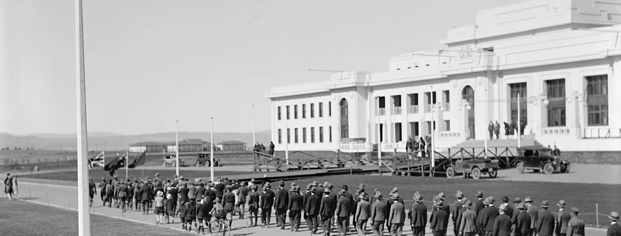 A parade marches in front of Parliament House. 