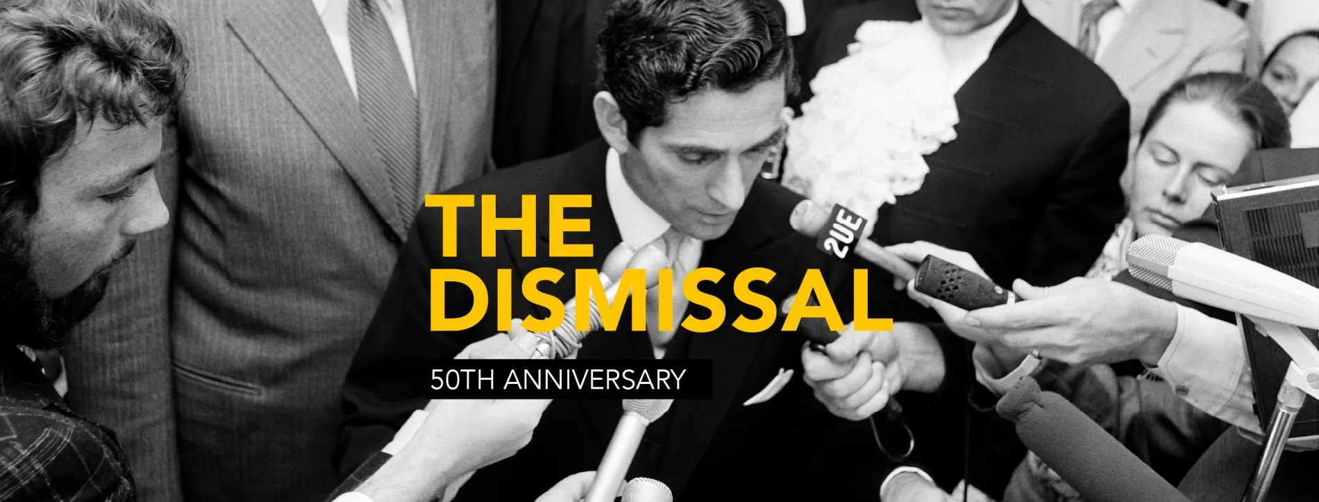 Many hands hold microphones toward David Smith's face as he reads the proclamation dissolving parliament. The words 'The Dismissal 50th Anniversary' appear over the top of the image.