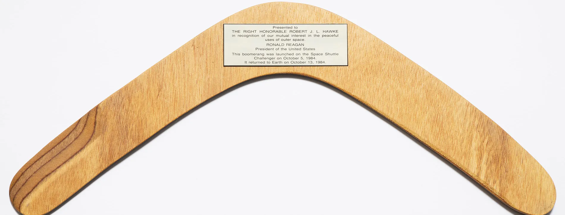 A wooden boomerang with a plaque presented to Robert (Bob) Hawke from US President Ronald Regan after the boomerang went into space on Space Shuttle Challenger, 1984.