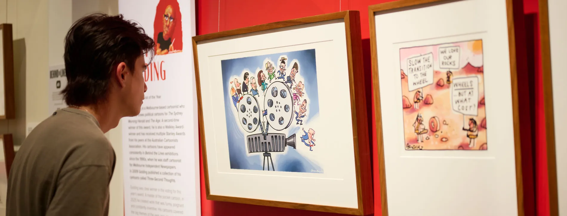 A man looks at framed cartoons in a political cartooning exhibition at Old Parliament House.