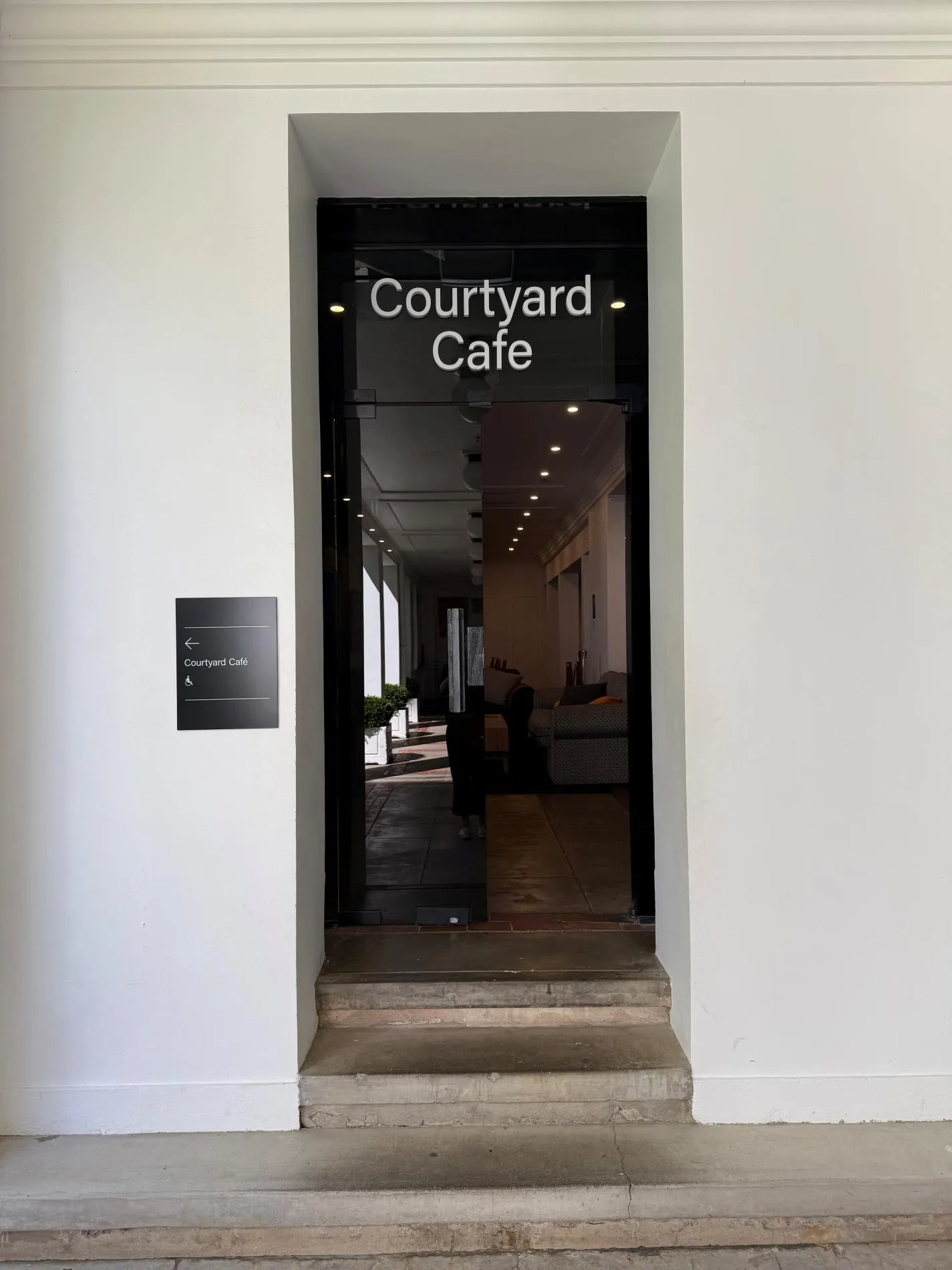 A glass door with the words Courtyard Cafe in white sans serif font.