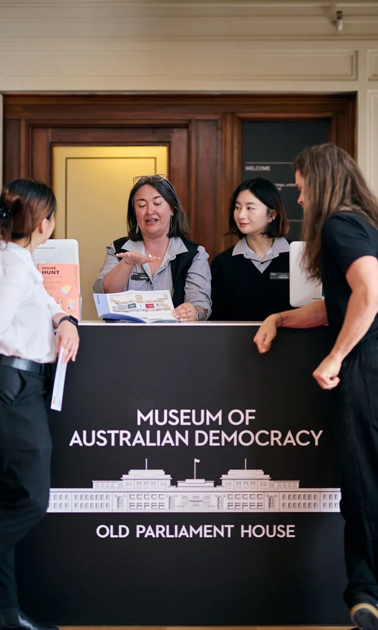 Museum staff show visitors to a brochure at the reception desk at MoAD at Old Parliament House.