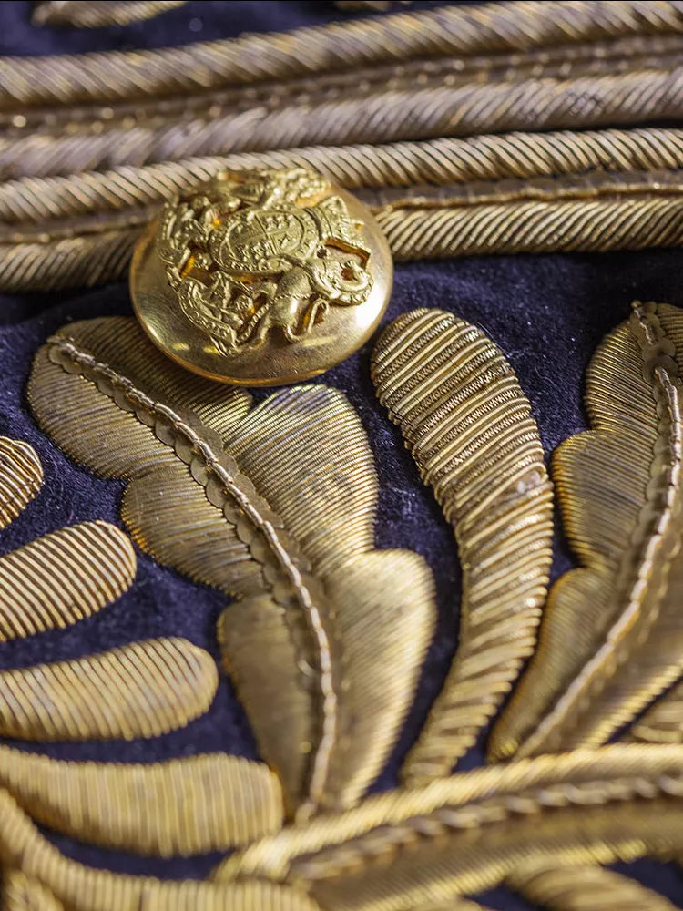 A close-up of an ornate coat with gold embroidered leaves and gold buttons embossed with the Australian coat of arms.