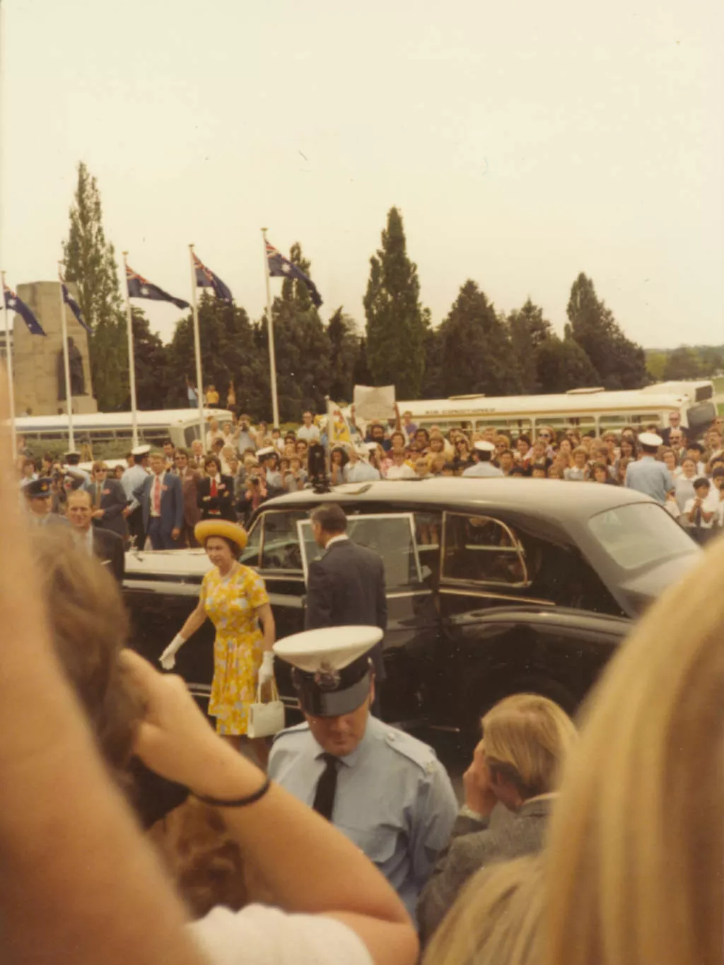 Queen Elizabeth II arrives at (Old) Parliament House amid a crowd holding placards and held back by police.