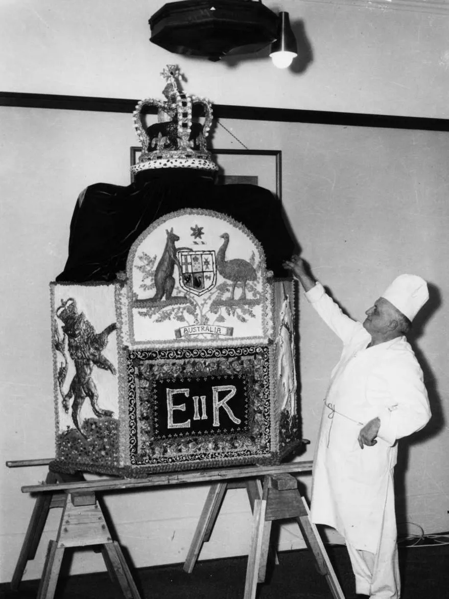 A man presents an ornate sculpture depicting the Australian coat of arms above the letters EIIR, flanked by a lion and unicorn and topped with a jewelled crown.