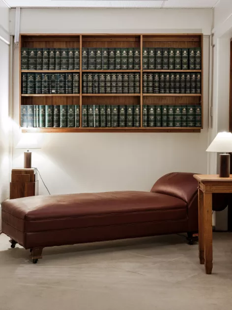 A chaise sofa with side table and bookshelf built into the wall