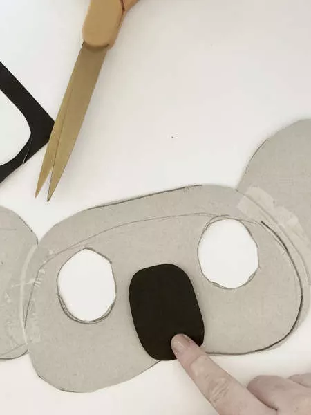 A koala mask with two eye holes cut out and a black nose. 