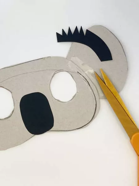 A koala mask with two eyes cut out, a black nose and black hair on the ears. 