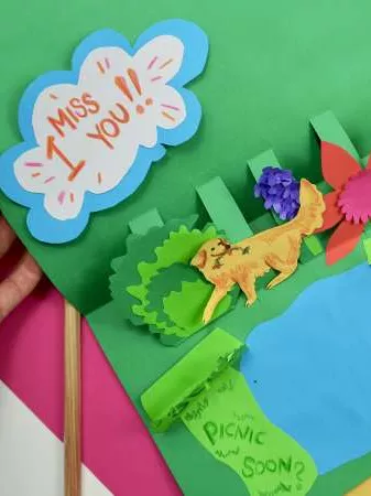 A colourful handmade card that features a lion in a forest next to a lake and the words 'I miss you'.