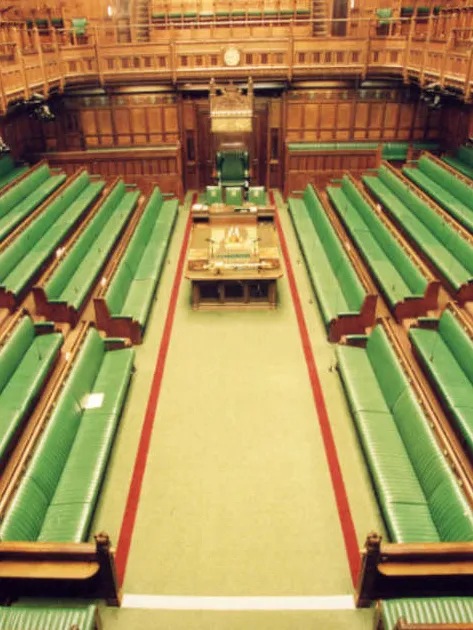 The UK House of Commons, with rows of green benches along two sides of the room facing the centre.