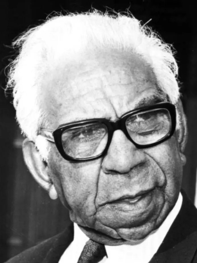 Portrait of Sir Douglas Nicholls, wearing a suit, tie and black-framed glasses.