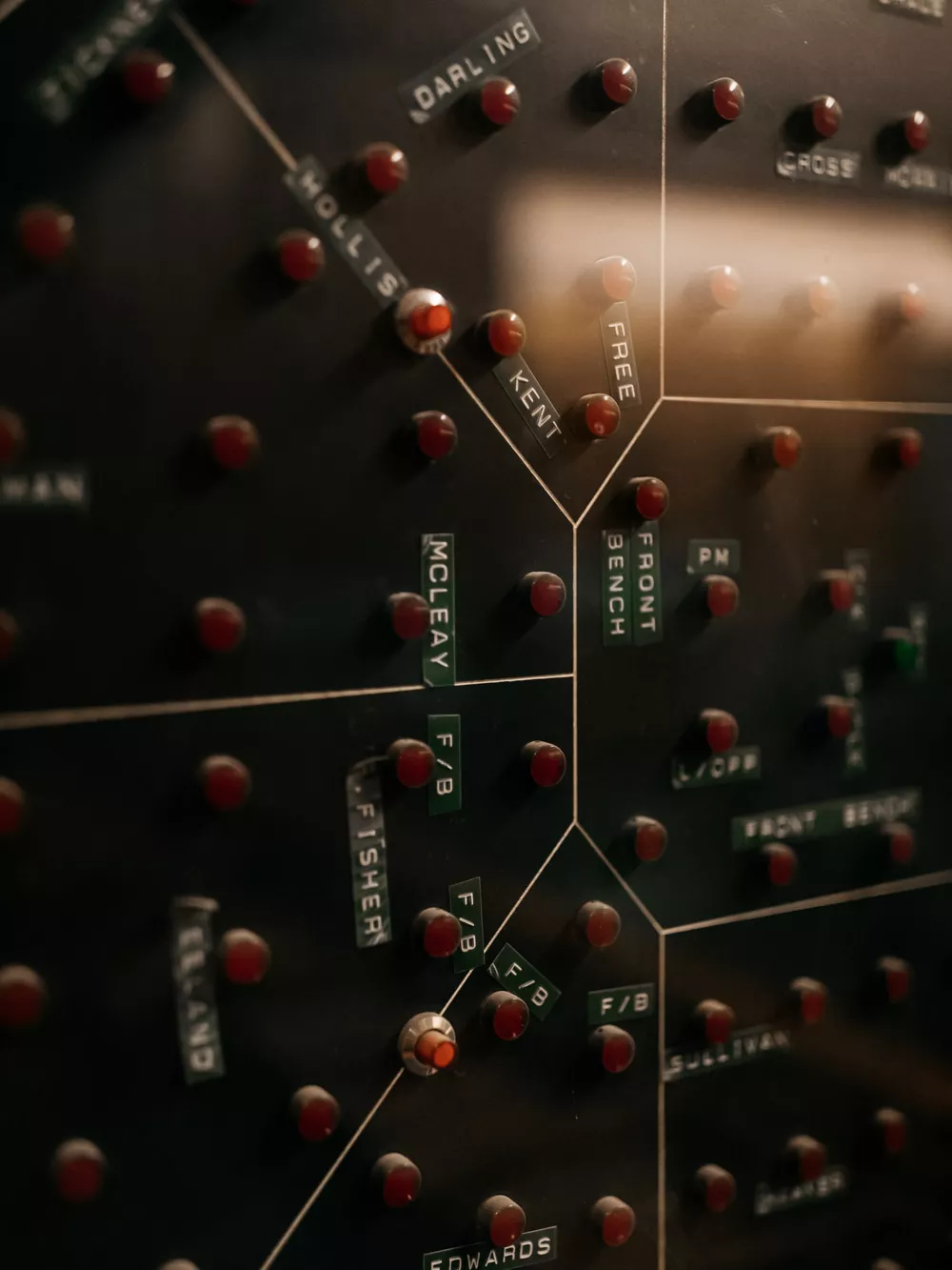 A close up of a layout of the House of Representatives Chamber with red lights representing each person in the chamber and black and black labels with names. 