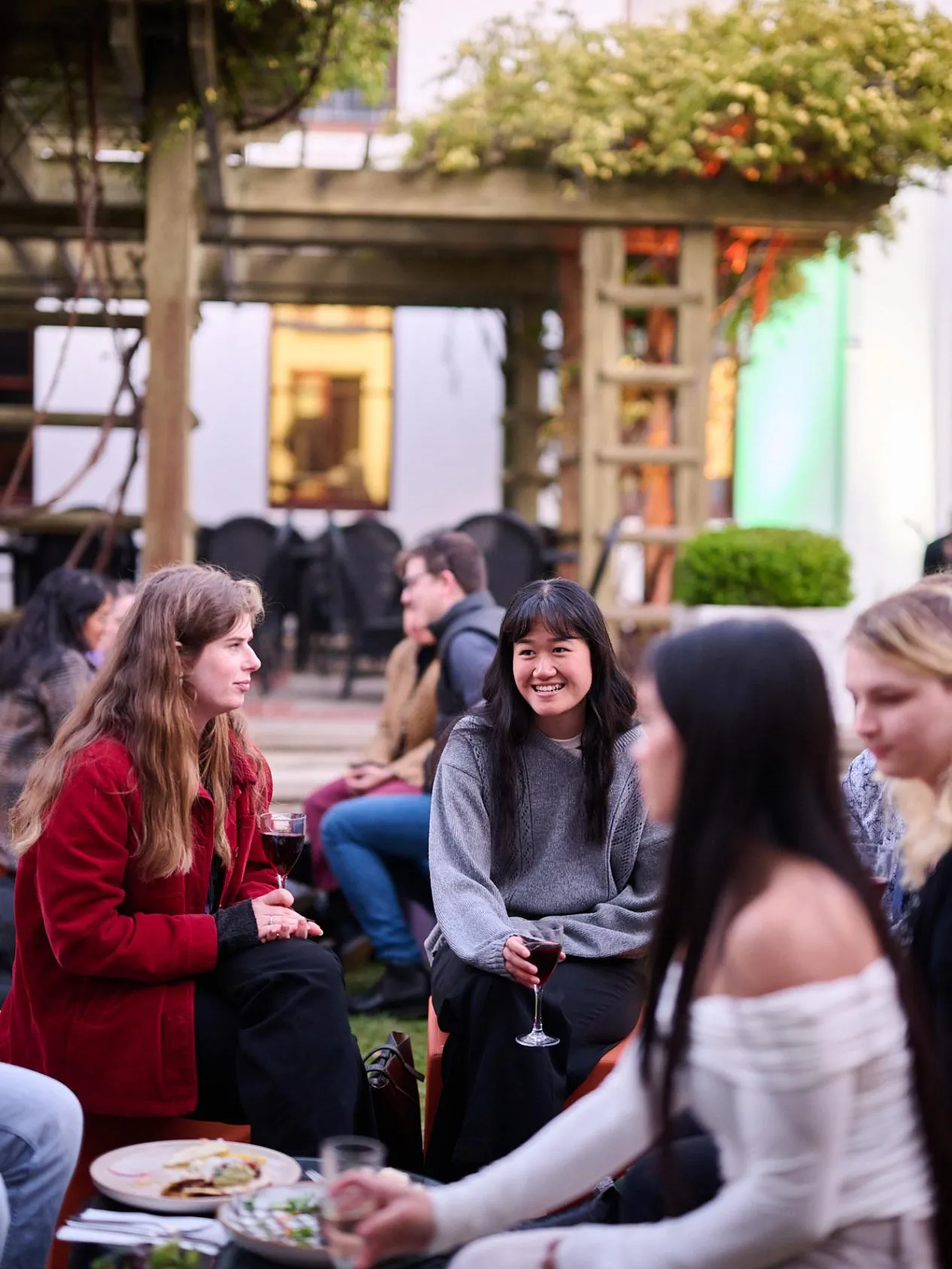People holding wine glasses sit in the House of Representatives Courtyard in Old Parliament House.