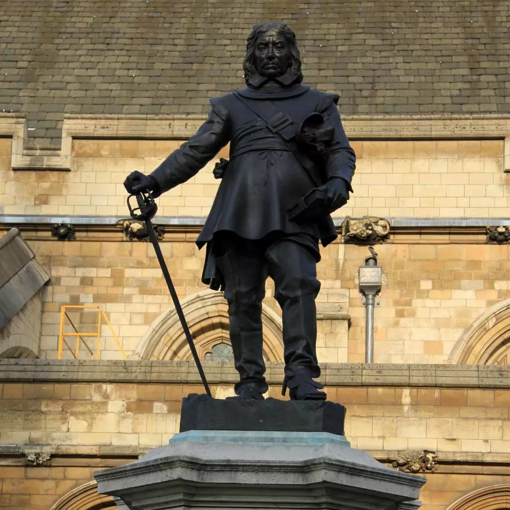 Statue of Oliver Cromwell holding a sword, on top of a sandstone column.