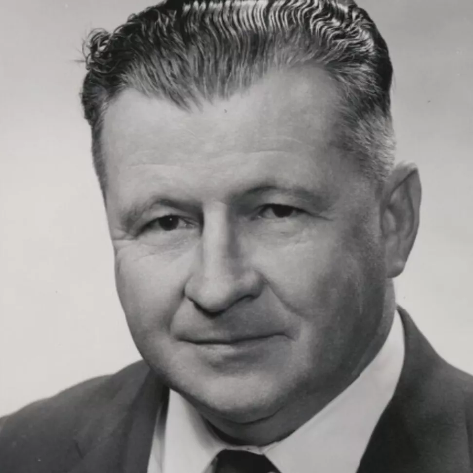 A black and white portrait photograph of Dr Felix Dittmer wearing a striped tie and lapel pin.