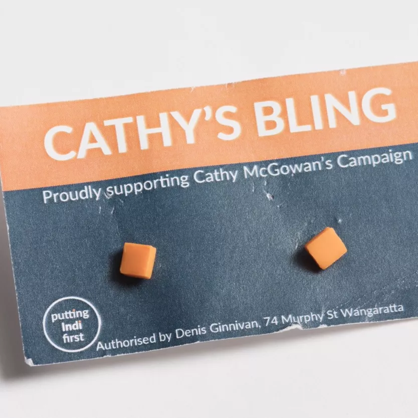 Photograph of two orange square earrings attached to a card with the lablel "CATHY'S BLING - Proudly supporting Cathy McGowan's Campaign"