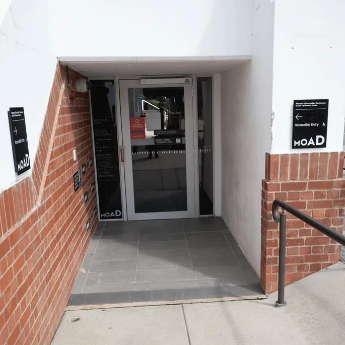 The entrance to a building with a glass and and a black and white sign with the words 'Accessible entry MoAD'.