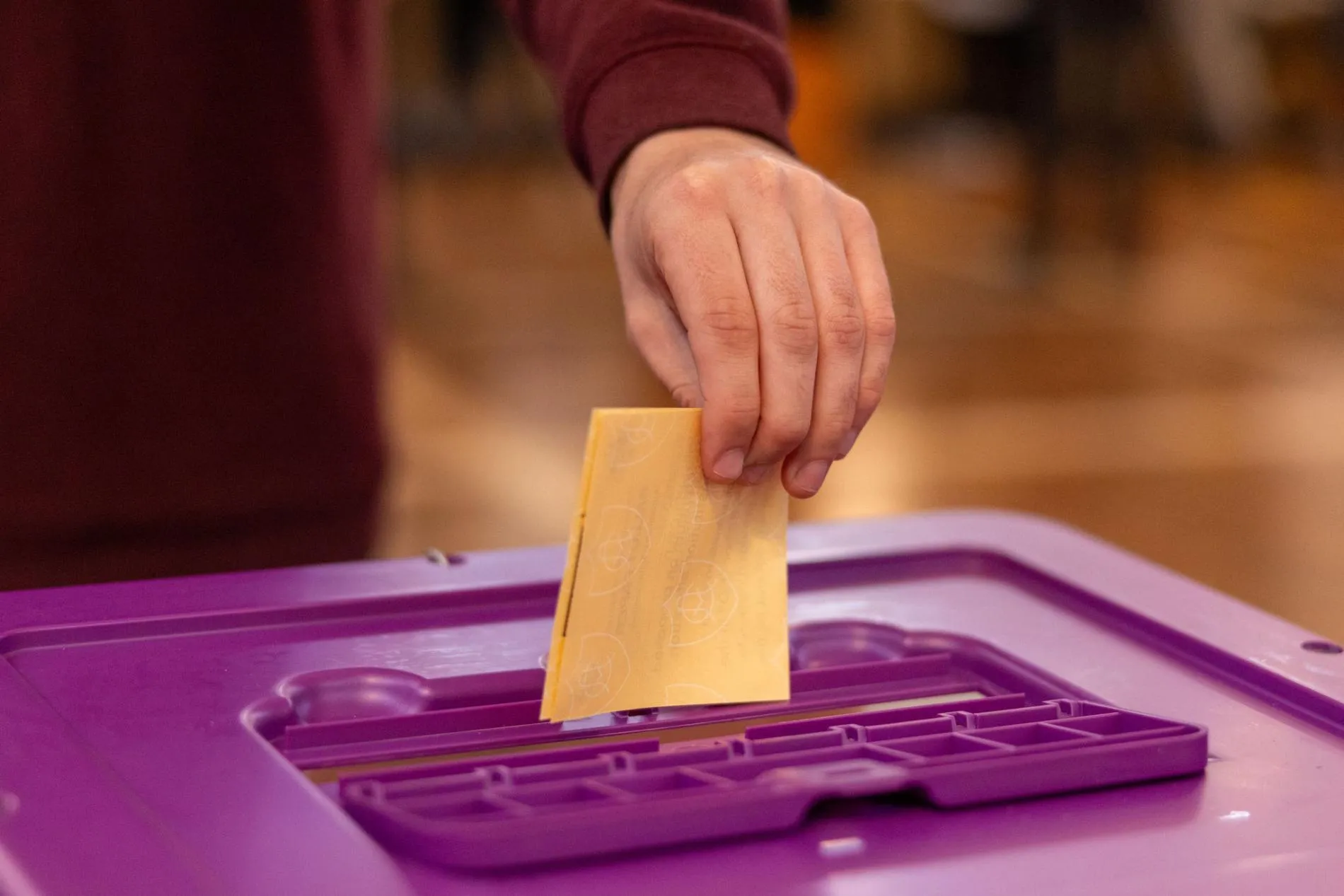 A voter puts a folded yellow ballot paper in a purple ballot box in Old Parliament House.