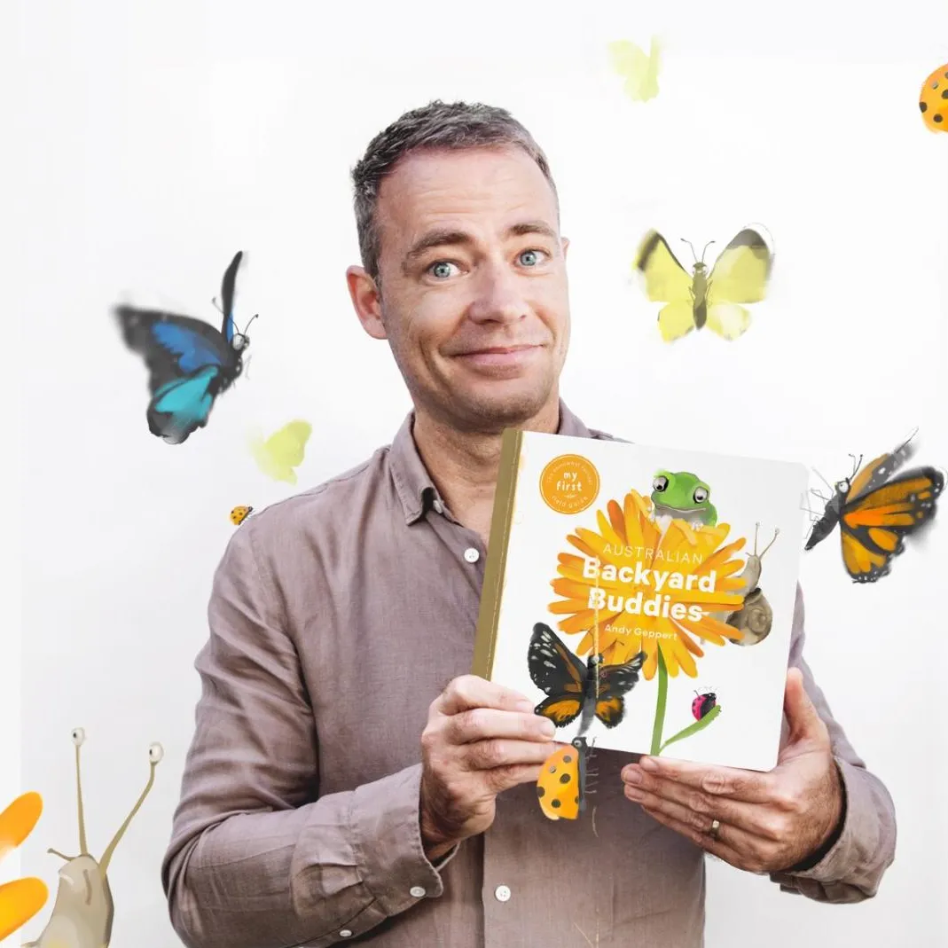 A man holds a book titled 'Backyard Buddies' against background illustrations of butterflies and a frog.