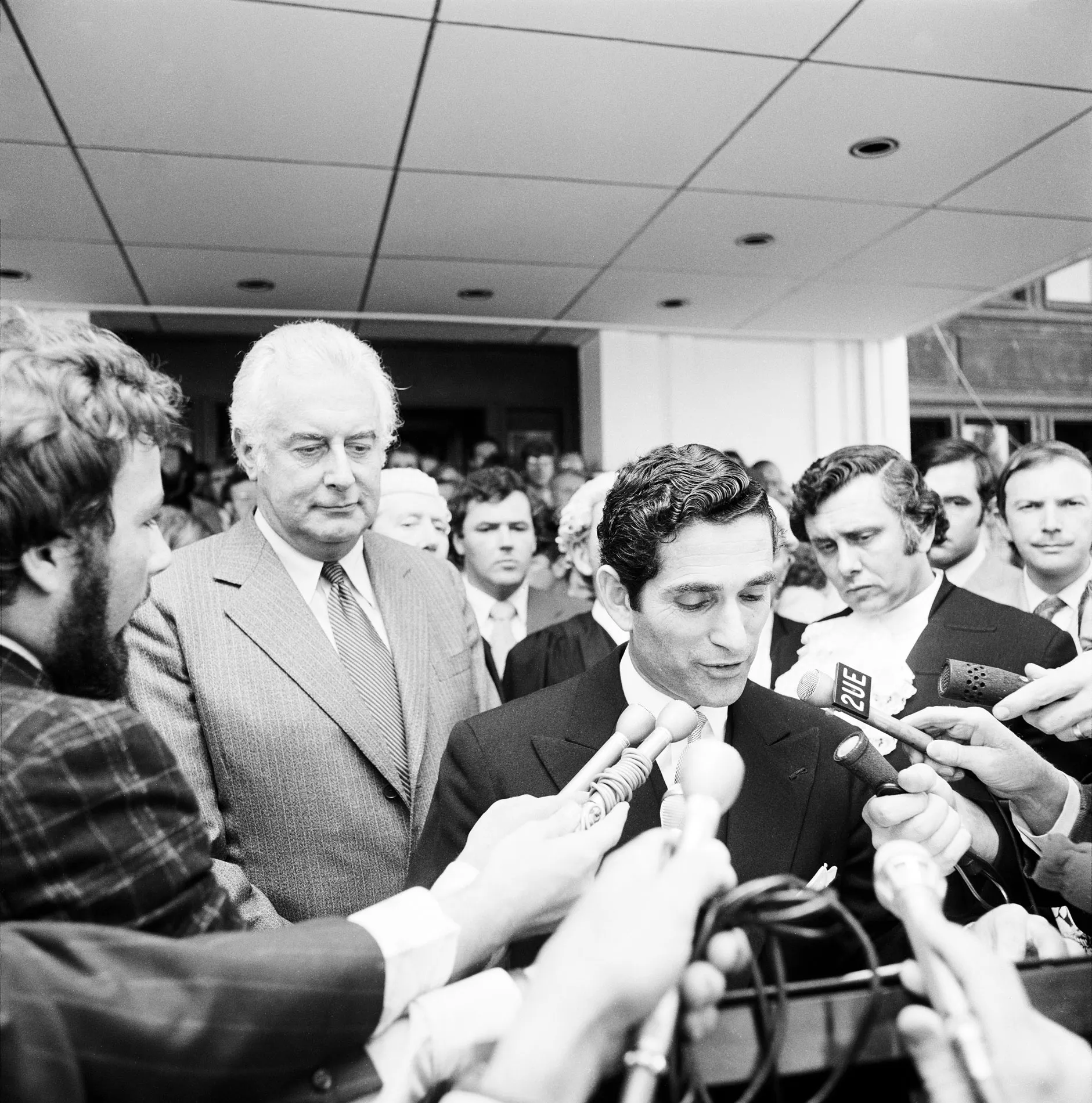 David Smith reads a proclamation on the steps of Parliament House watched by Gough Whitlam and crowds.