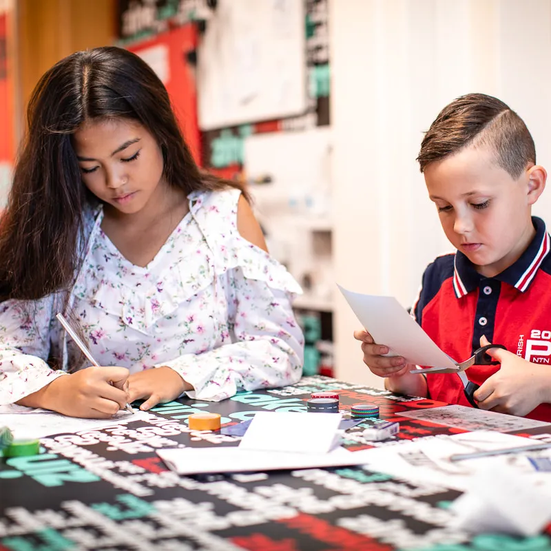 Two kids write and craft in Old Parliament House.