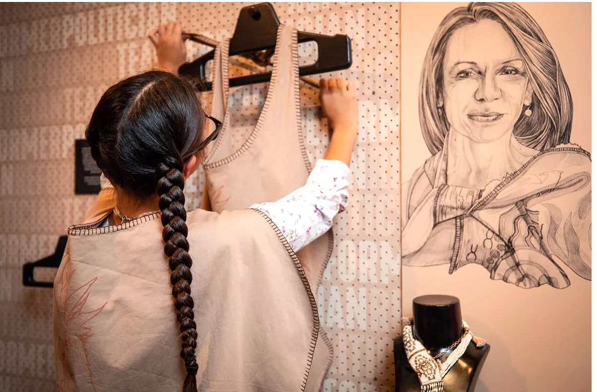 An older girl hanging a garment onto a hanger